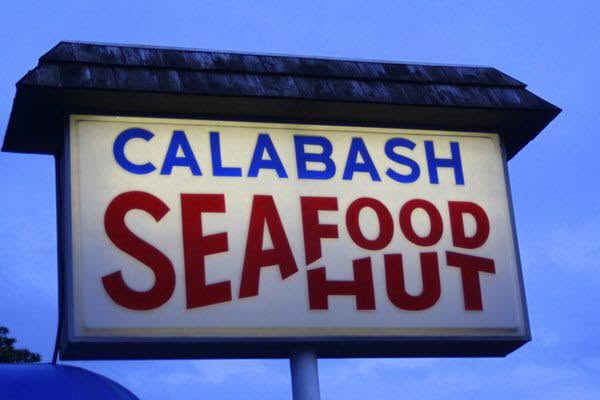The Calabash Seafood Hut sign lit against the evening sky