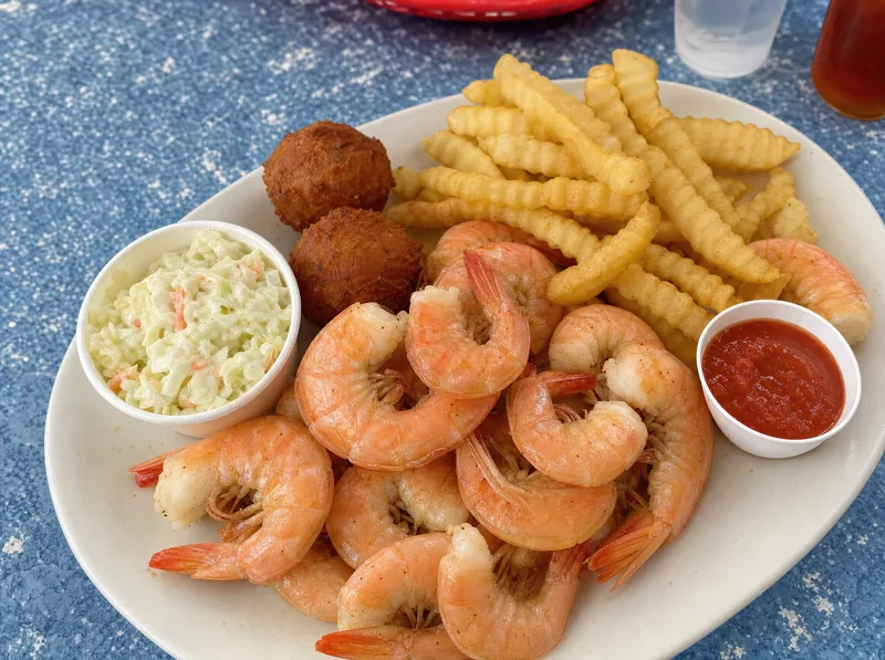 Boiled peel-and-eat shrimp plate with cocktail sauce, hushpuppies and slaw
